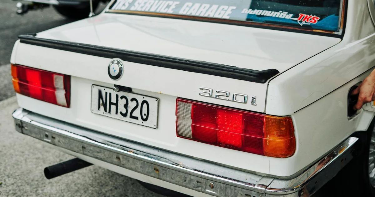 White car parked in a lot with visible tail lights and garage.
