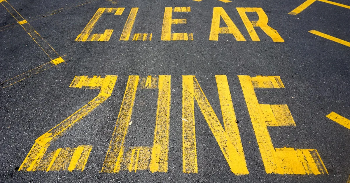 Yellow clear zone markings on asphalt in a parking area.