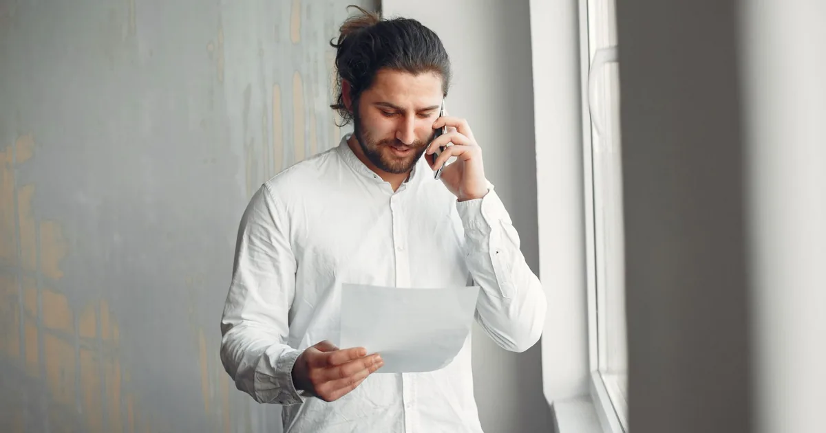 A man holding a document while talking on the phone