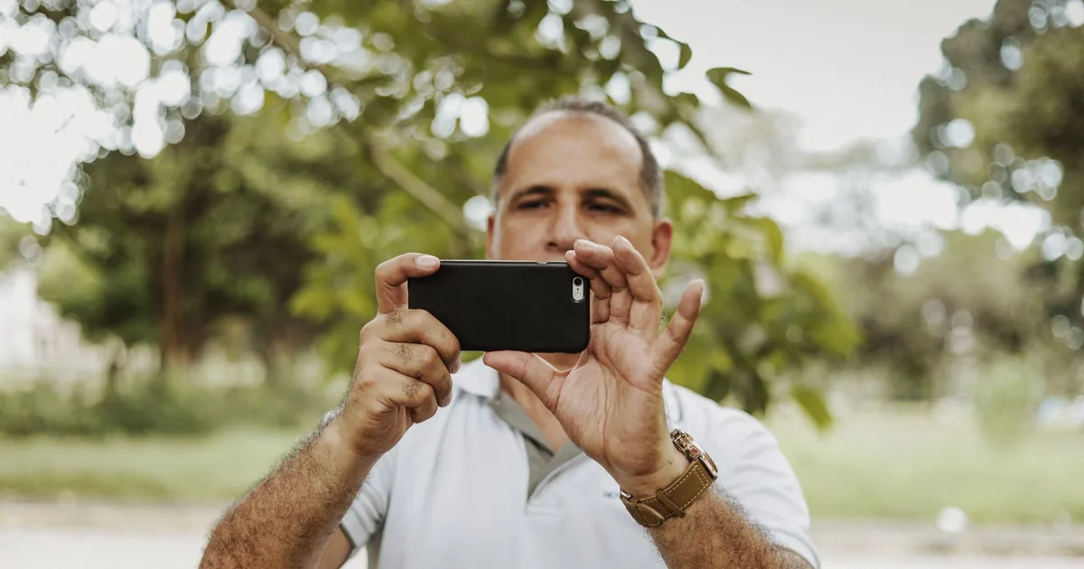 A man taking a photo with his smartphone outdoors