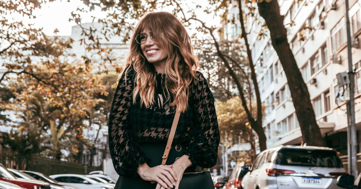 A smiling woman on a city street lined with parked cars