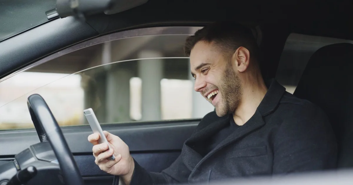 A young man using his smartphone inside a car